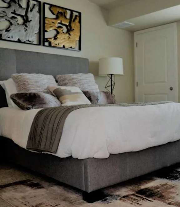 A bedroom with a large bed and a chair.