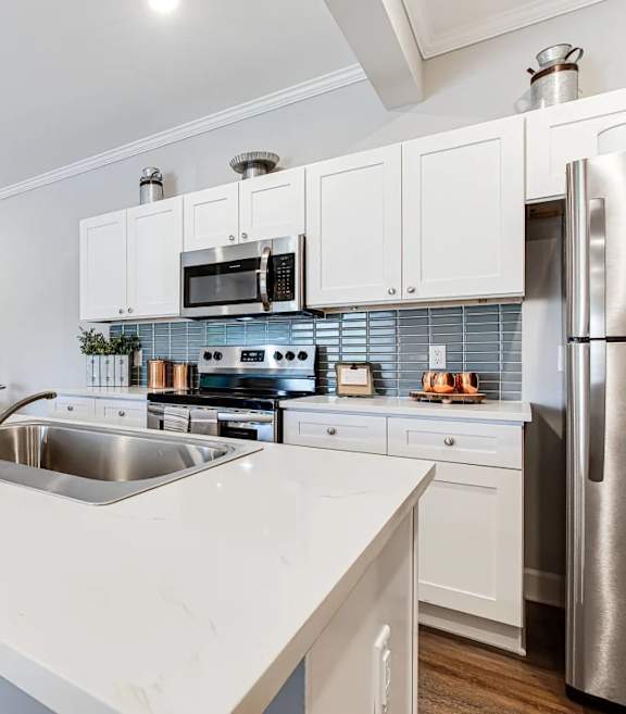 A modern kitchen with a white countertop and stainless steel appliances.