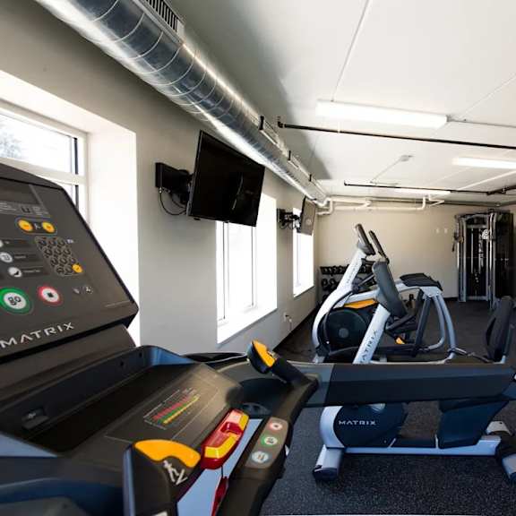A gym with treadmills and a television mounted on the wall.