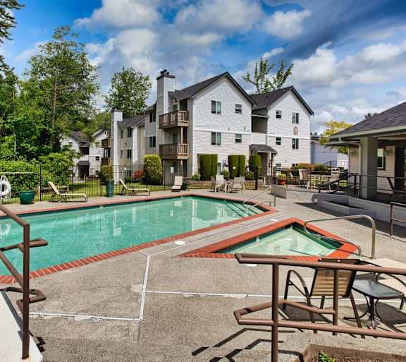 A pool with a table and chairs in front of a white building.
