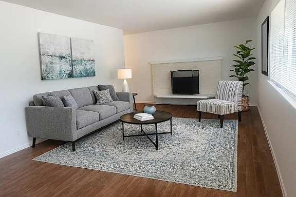 A living room with a grey couch, a coffee table, a lamp, a fireplace, and a chair.
