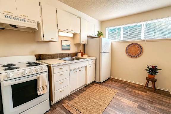 A kitchen with white appliances and wooden floors.