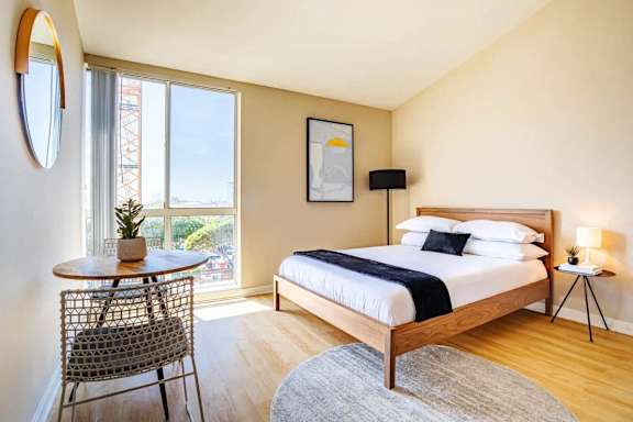a bedroom with a bed and a table and a window