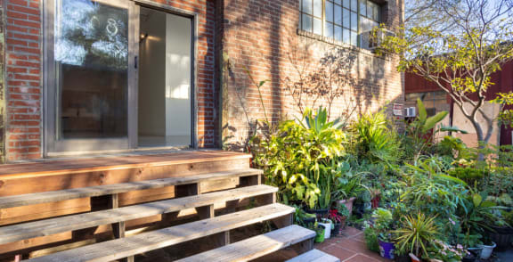 the front of a brick house with a large wooden porch and potted plants