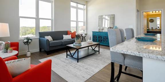 A modern living room with a grey sofa, a red armchair, and a marble table.