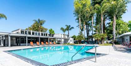 A swimming pool with a metal ladder and orange chairs.
