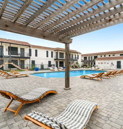 A patio with a pool and sun loungers.