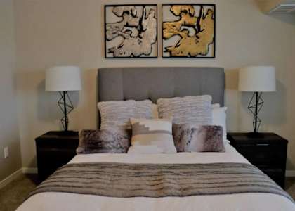 A bedroom with a large bed and two lamps on either side.
