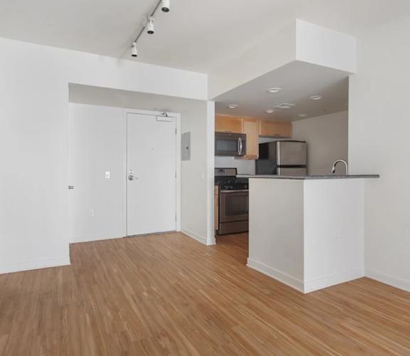 A kitchen with a white counter and wooden floors.