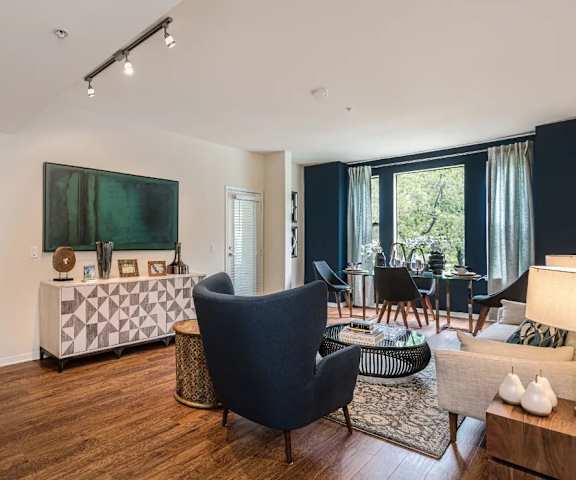 A living room with a dark blue chair and a patterned sofa.