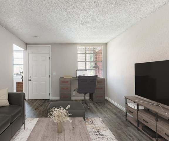 A living room with a grey couch, a wooden coffee table, and a flat screen TV.