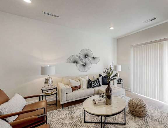 A modern living room with a white sofa, a round coffee table, and a large abstract wall art.
