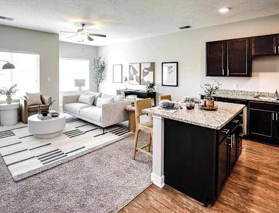 A modern kitchen with a black countertop and a dining area with a white rug.