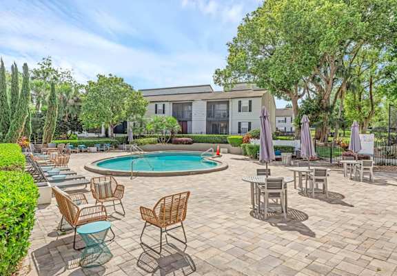 A pool surrounded by chairs and umbrellas with a building in the background.