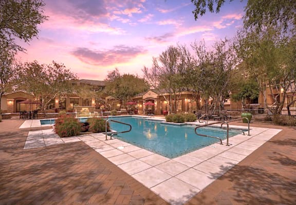 A pool surrounded by a patio and trees.