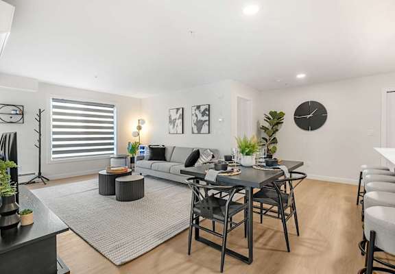 A modern living room with a grey sofa, a black coffee table, and a grey rug.at Skyway Apartments, Calgary, AB T3B 5V6