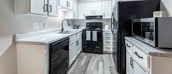 A kitchen with black appliances and white cabinets.