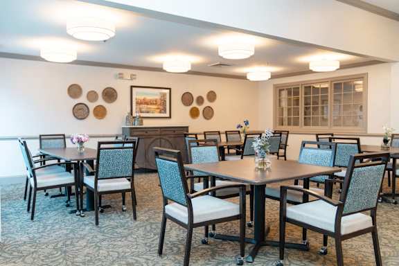 A dining room with a table surrounded by chairs.