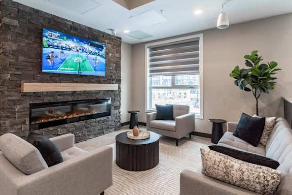 A living room with a stone fireplace and a flat screen TV mounted above it.at Skyway Apartments, Calgary, AB T3B 5V6