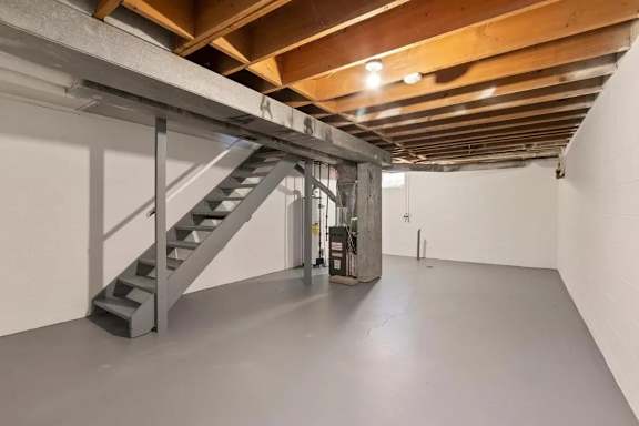 A staircase in a room with wooden beams on the ceiling.