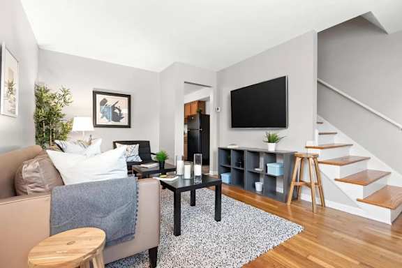 A living room with a couch, a table, a television, and a staircase.