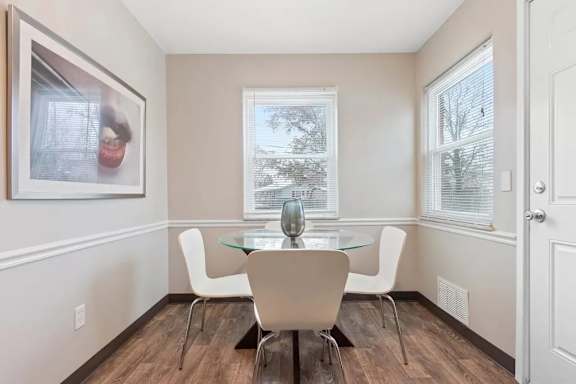 A dining room with a glass table and white chairs.