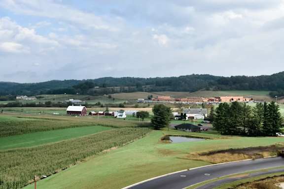 A road with a curve in the foreground with a farm in the background.