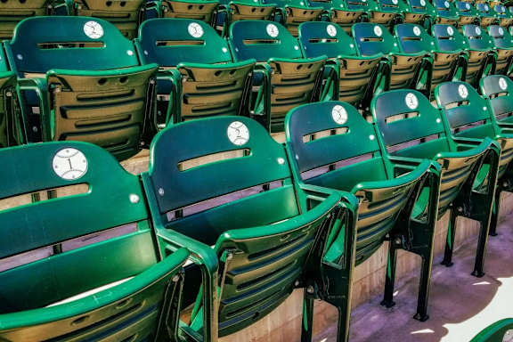 A row of green stadium seats with white logos on the back.