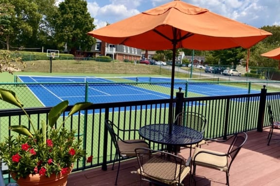 a tennis court with a table and chairs and an umbrella