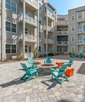 an outdoor patio with chairs and tables in front of an apartment building