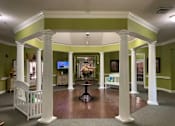 Thumbnail 2 of 5 - a large living room with columns and a table with flowers