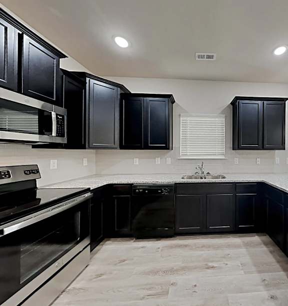 A kitchen with black cabinets and a marble countertop.