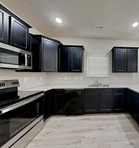 A kitchen with black cabinets and a white countertop.