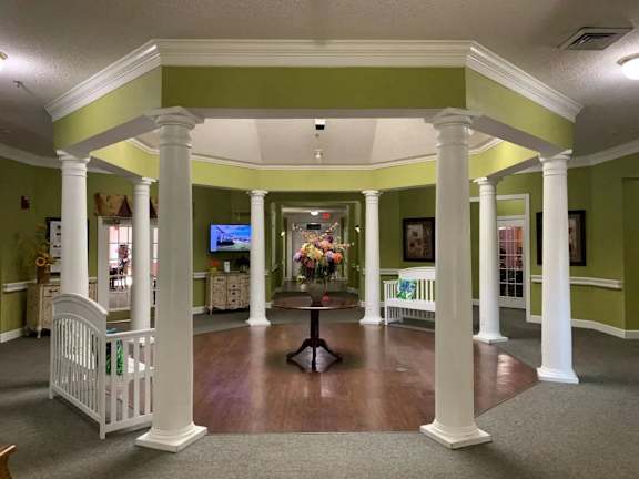 a large living room with columns and a table with flowers