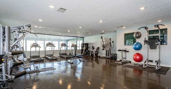a gym with exercise equipment on the floor and a window