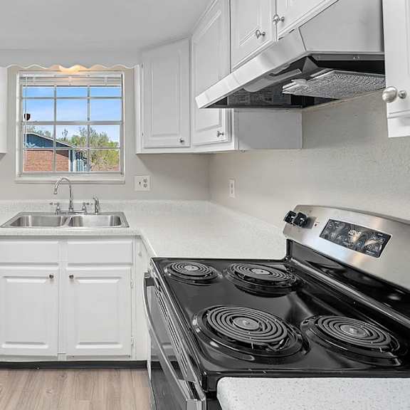 A kitchen with white cabinets and a black stove top.