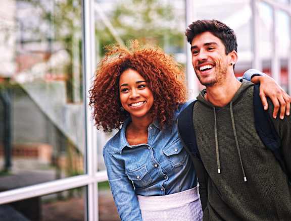 A man and a woman are standing close together, smiling.