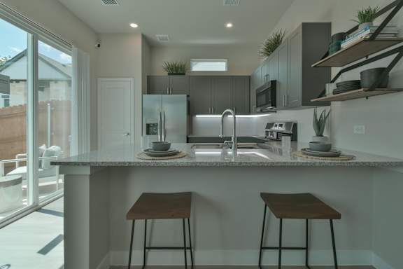 A modern kitchen with a dining table set for two. at Avilla Berry Creek Highlands  Apartments, Texas, 78633