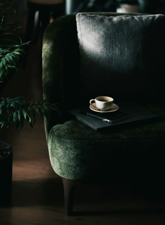 Cup of Coffee on Laptop on Green Sofa