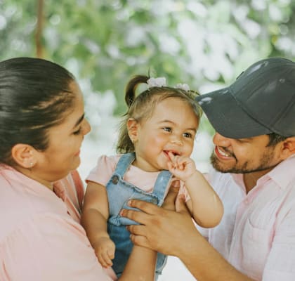 A woman and a man are holding a baby girl.