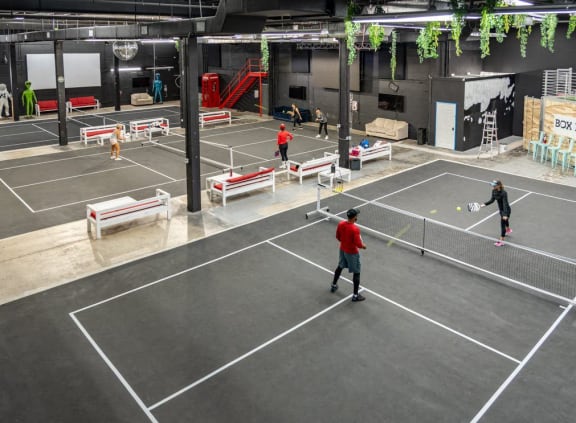 people playing tennis in a large indoor tennis court