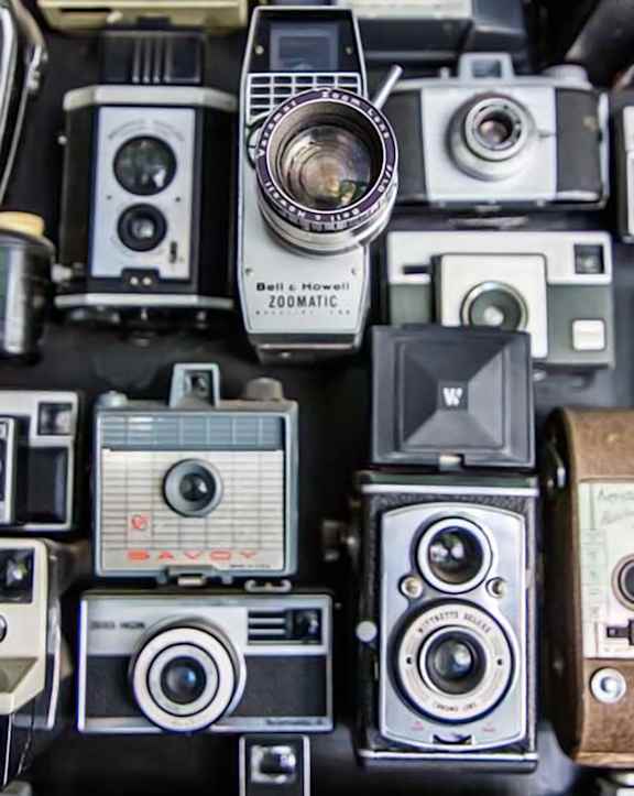 A collection of old cameras with one labeled "Poland Land Camera".