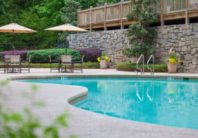 a swimming pool with patio furniture and umbrellas at Elme Cumberland Apartments, Smyrna, GA, 30080