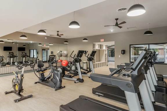 A spacious gym with a variety of equipment including treadmills, stationary bikes, and weight machines.
