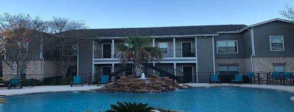 a large pool with a palm tree in front of an apartment building