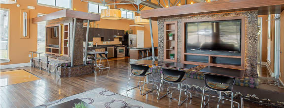 a large living room with a large tv and a kitchen in the background