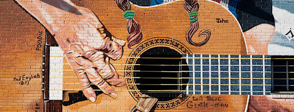 A mural of a hand holding a guitar with the words "for true gentle man" written on it.
