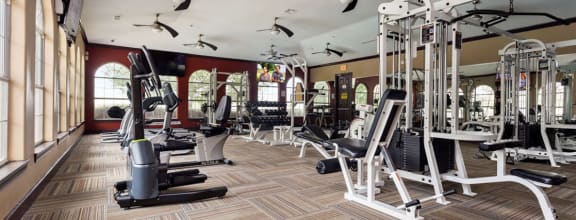 a gym with cardio equipment on the floor and a lot of windows