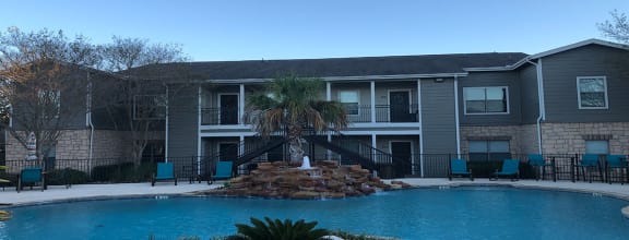 a large pool with a palm tree in front of an apartment building