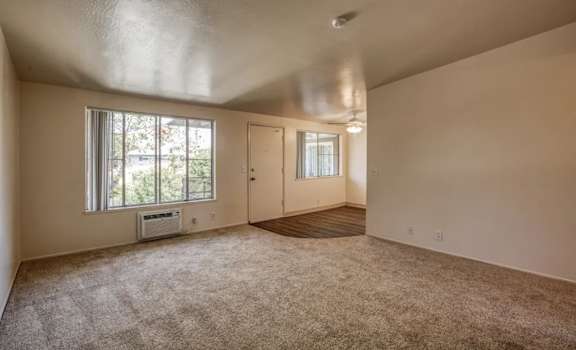 A room with a window and a door is empty and waiting to be furnished.